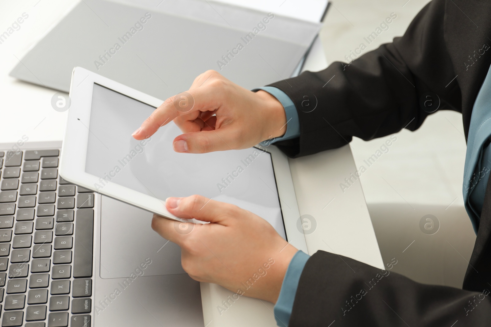 Photo of Businesswoman using tablet at white table indoors, closeup. Modern technology