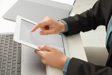 Photo of Businesswoman using tablet at white table indoors, closeup. Modern technology