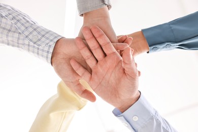 Photo of Teamwork. Group of employees joining hands in office, bottom view