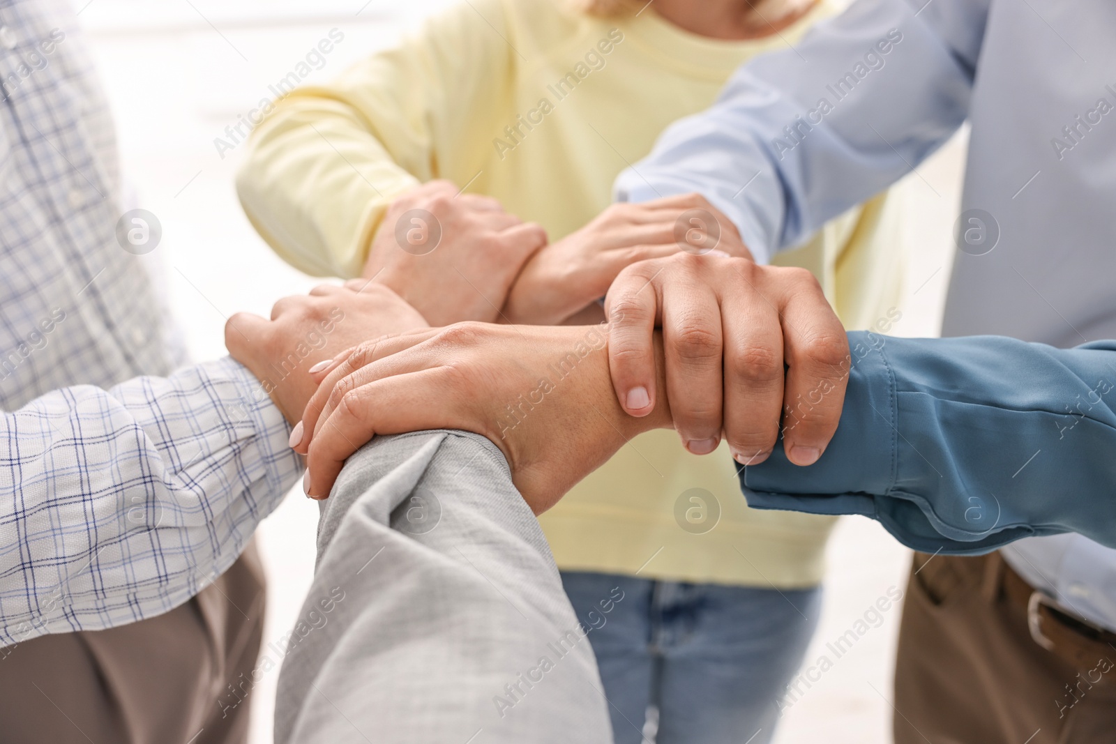 Photo of Teamwork. Group of employees joining hands in office, closeup