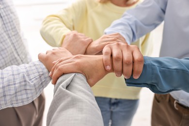 Photo of Teamwork. Group of employees joining hands in office, closeup