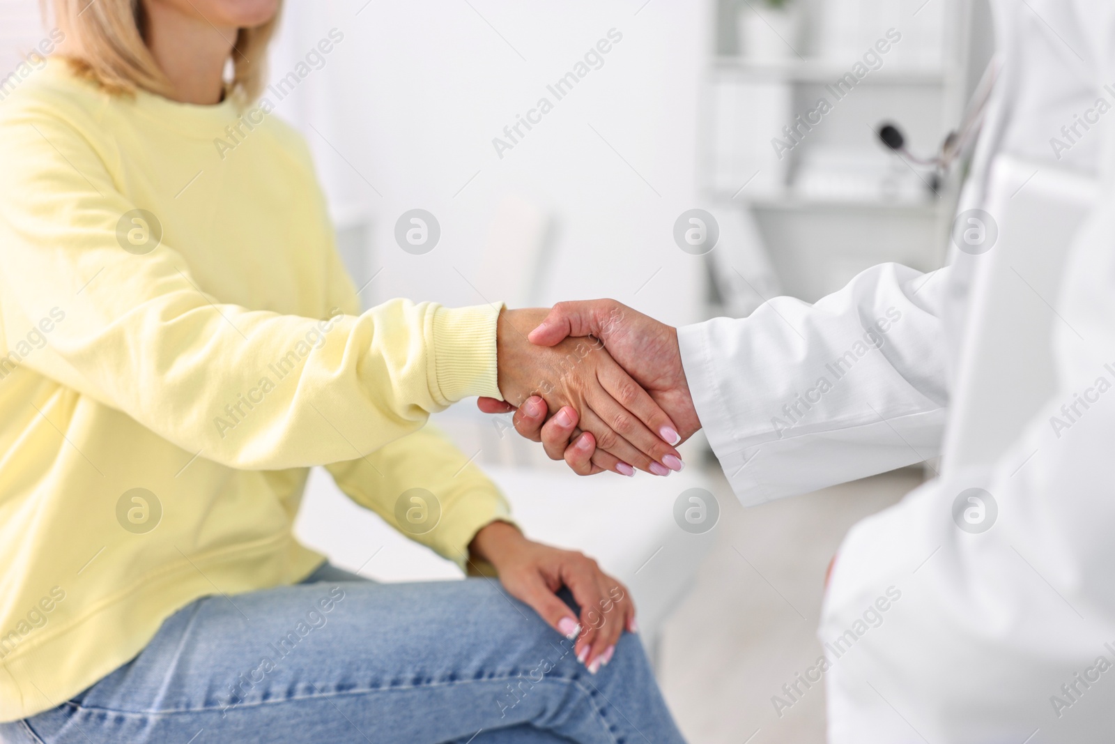 Photo of Healthcare worker shaking hands with patient in hospital, closeup