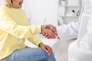 Photo of Healthcare worker shaking hands with patient in hospital, closeup