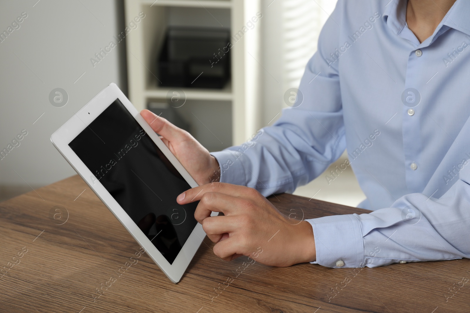 Photo of Businessman using tablet at wooden table, closeup. Modern technology