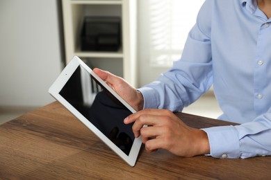 Photo of Businessman using tablet at wooden table, closeup. Modern technology