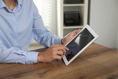 Photo of Businessman using tablet at wooden table, closeup. Modern technology