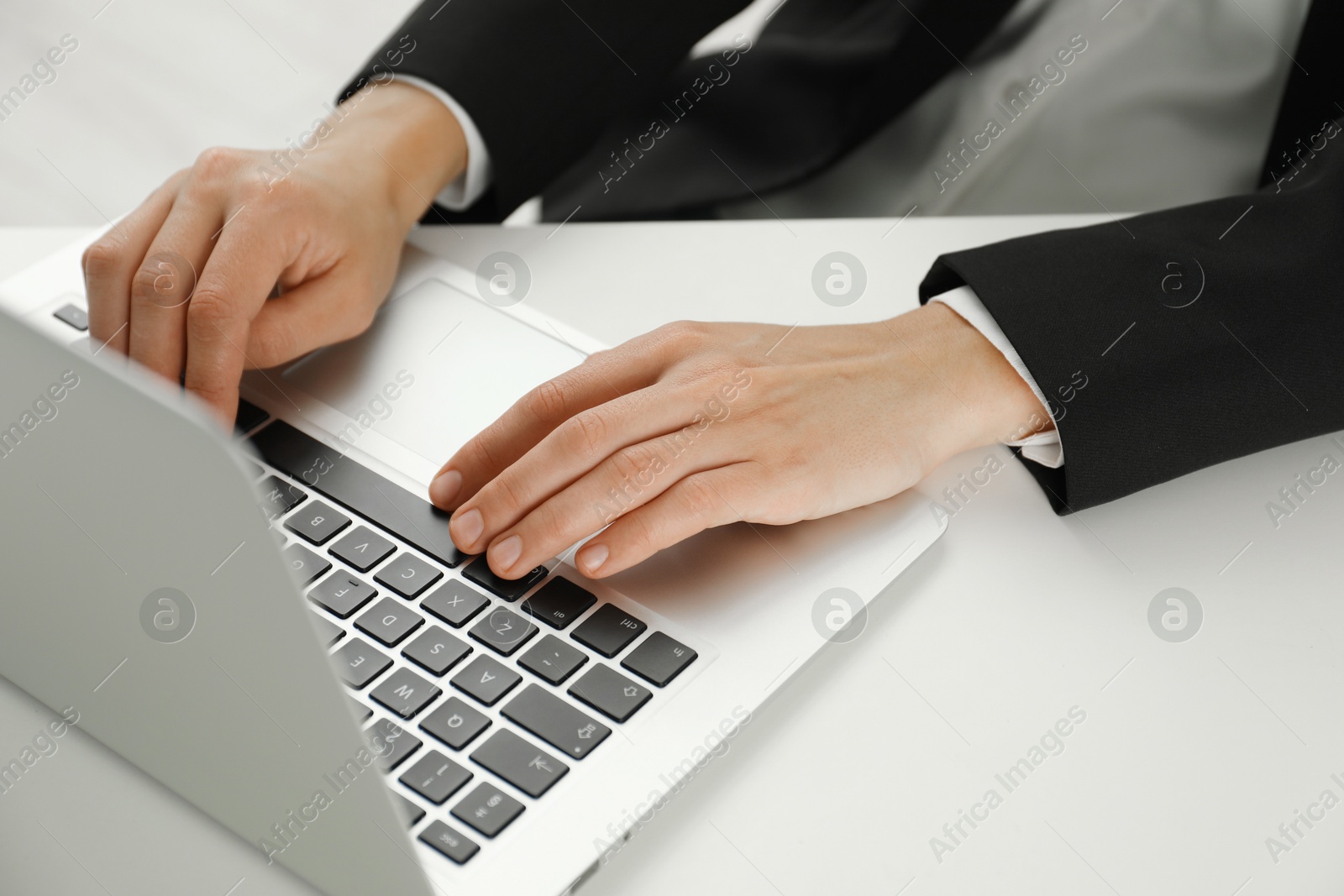 Photo of Businesswoman using laptop at white table indoors, closeup. Modern technology