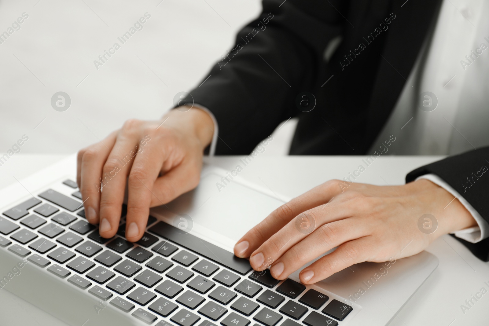 Photo of Businesswoman using laptop at white table indoors, closeup. Modern technology