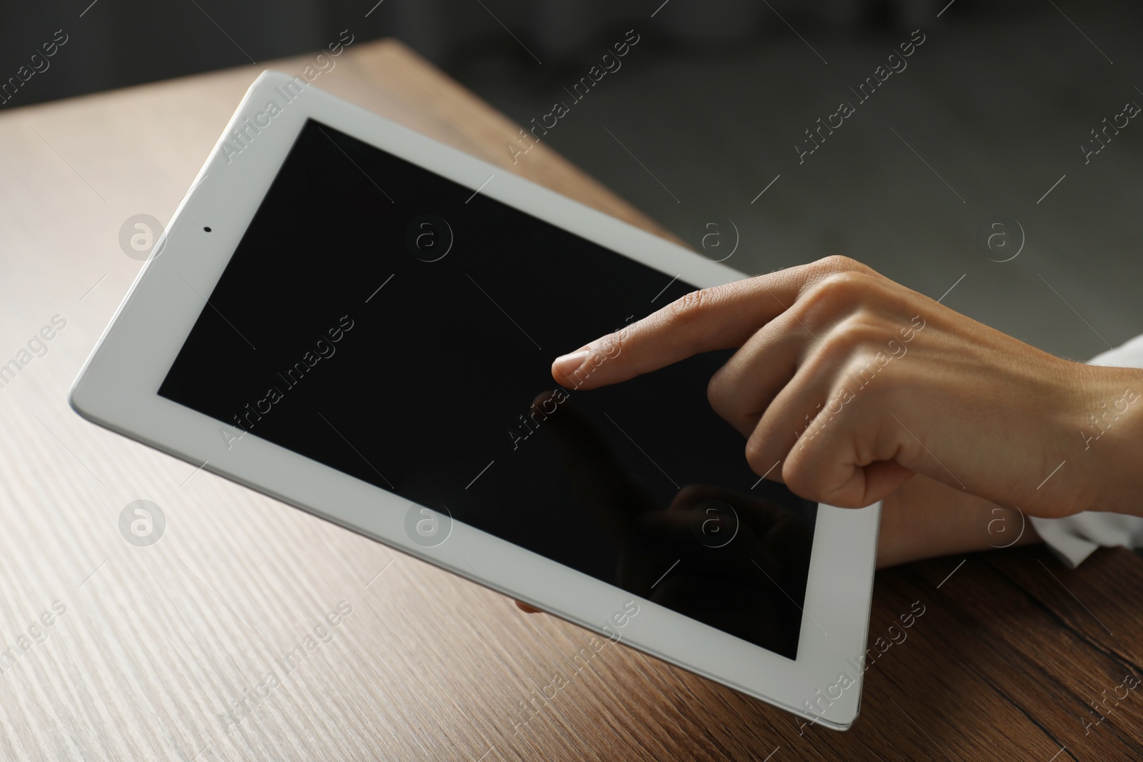 Photo of Businesswoman using tablet at wooden table indoors, closeup. Modern technology