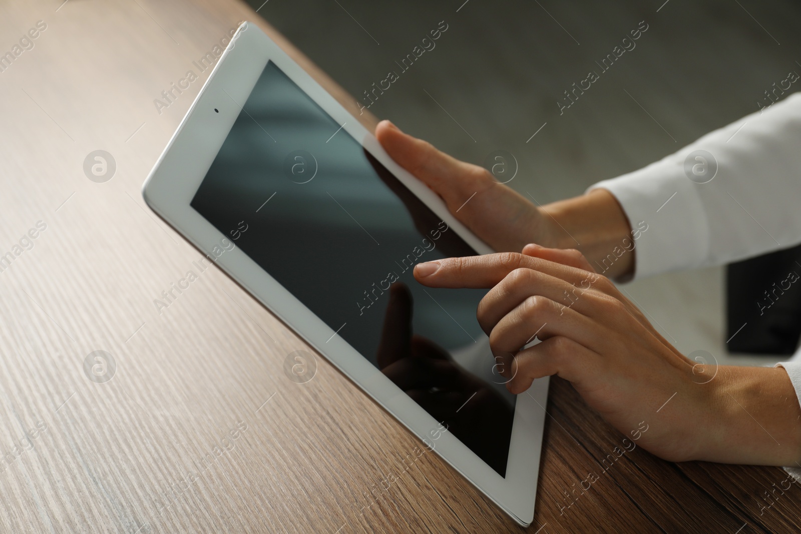 Photo of Businesswoman using tablet at wooden table indoors, closeup. Modern technology