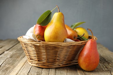 Photo of Ripe juicy pears in wicker basket on wooden table against grey background