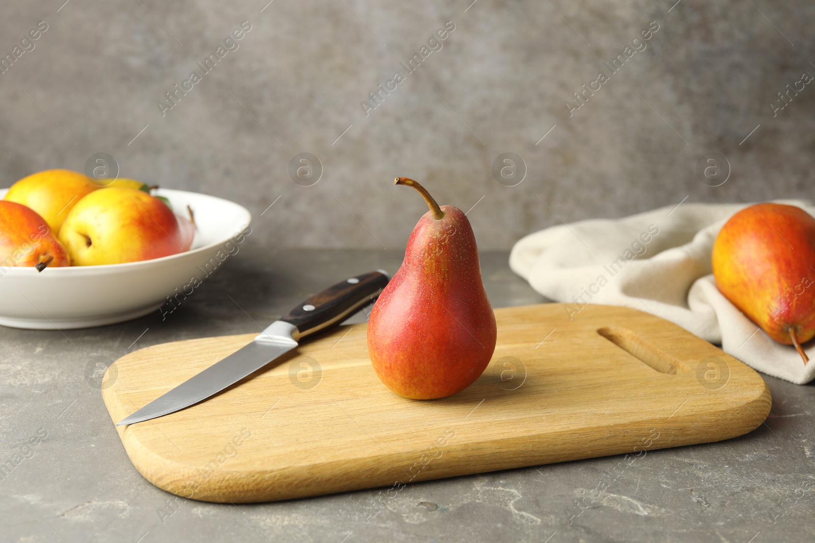 Photo of Ripe juicy pears and knife on grey textured table