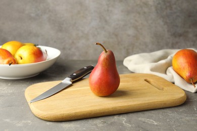 Photo of Ripe juicy pears and knife on grey textured table