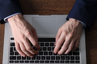 Photo of Businessman using laptop at wooden table, top view. Modern technology