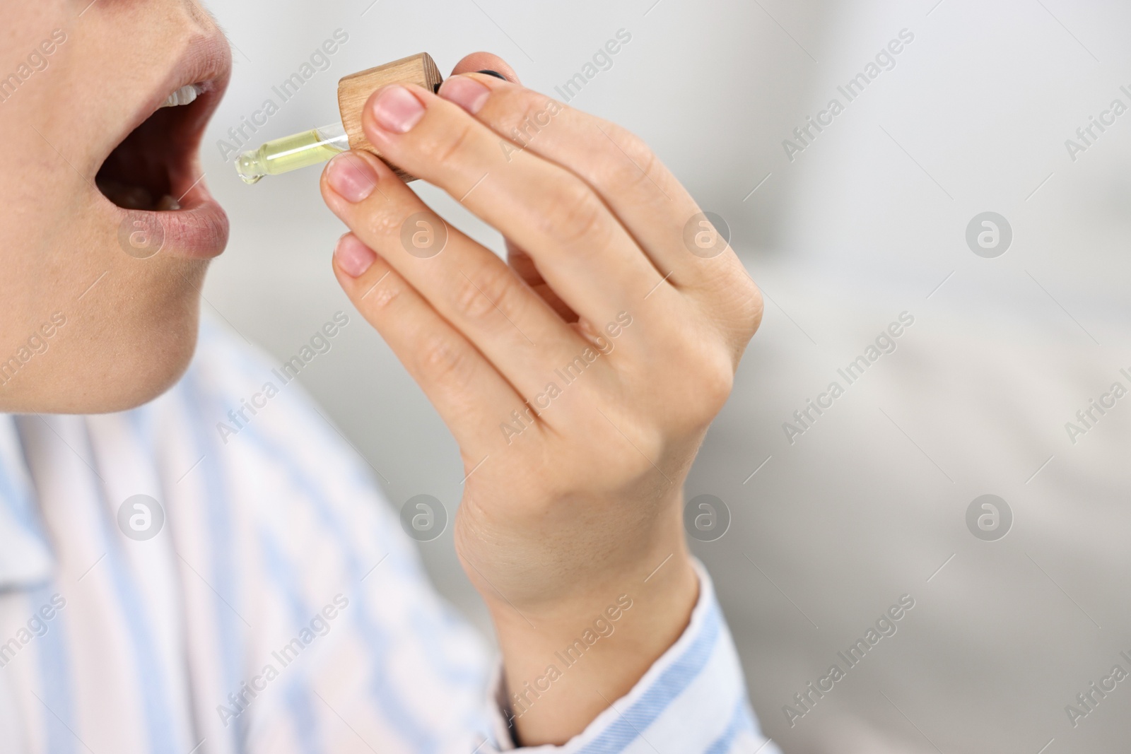 Photo of Young woman taking CBD tincture indoors, closeup. Space for text