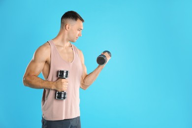 Photo of Man exercising with dumbbells on light blue background, space for text