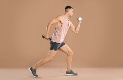 Photo of Man exercising with dumbbells on light brown background