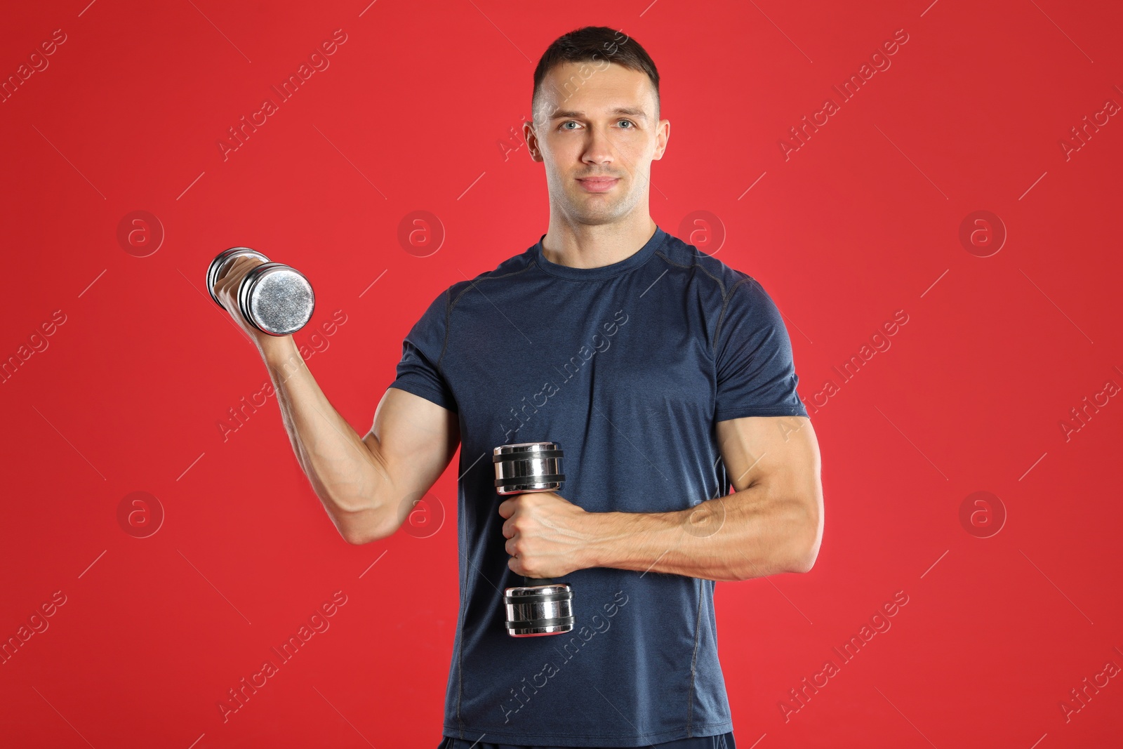 Photo of Man exercising with dumbbells on red background