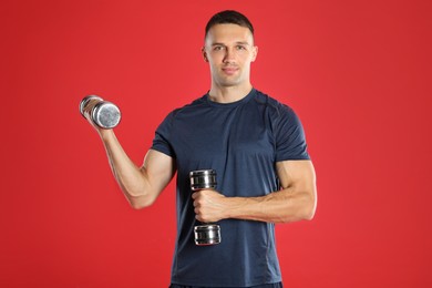 Photo of Man exercising with dumbbells on red background