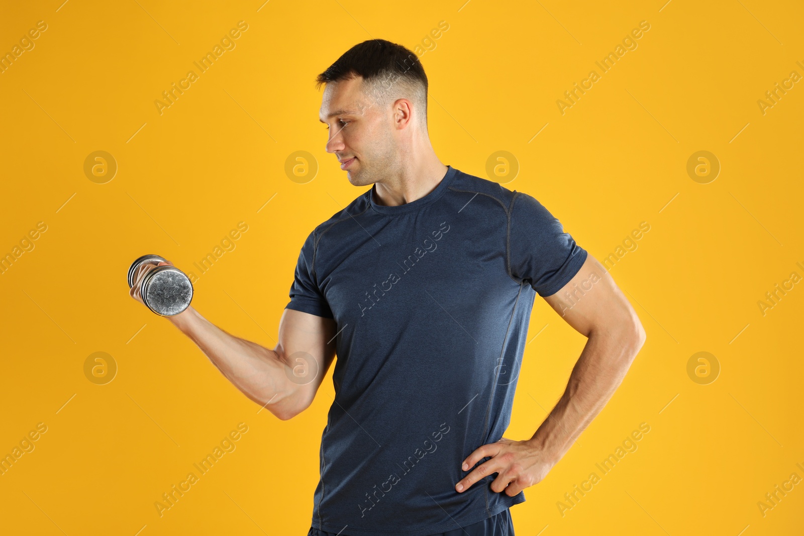 Photo of Man exercising with dumbbell on yellow background