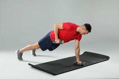 Photo of Man exercising with dumbbells on grey background