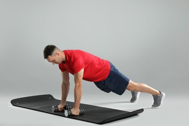 Photo of Man exercising with dumbbells on grey background