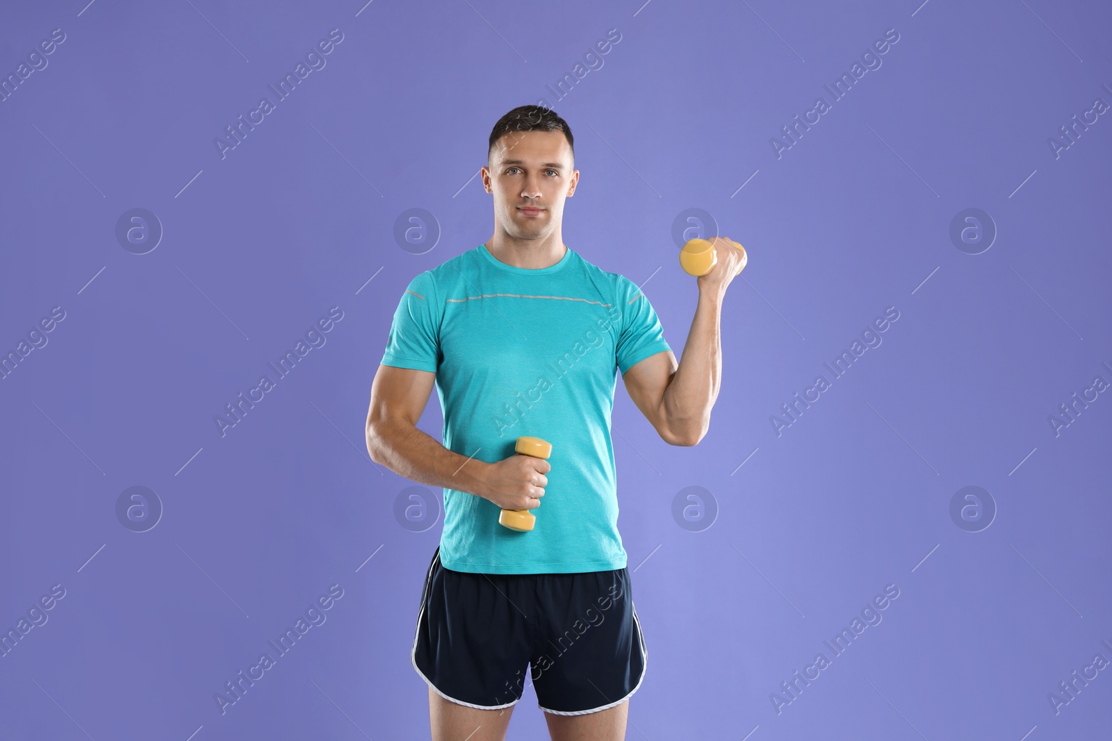 Photo of Man exercising with dumbbells on violet background