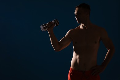 Photo of Man exercising with dumbbell on dark blue background, space for text