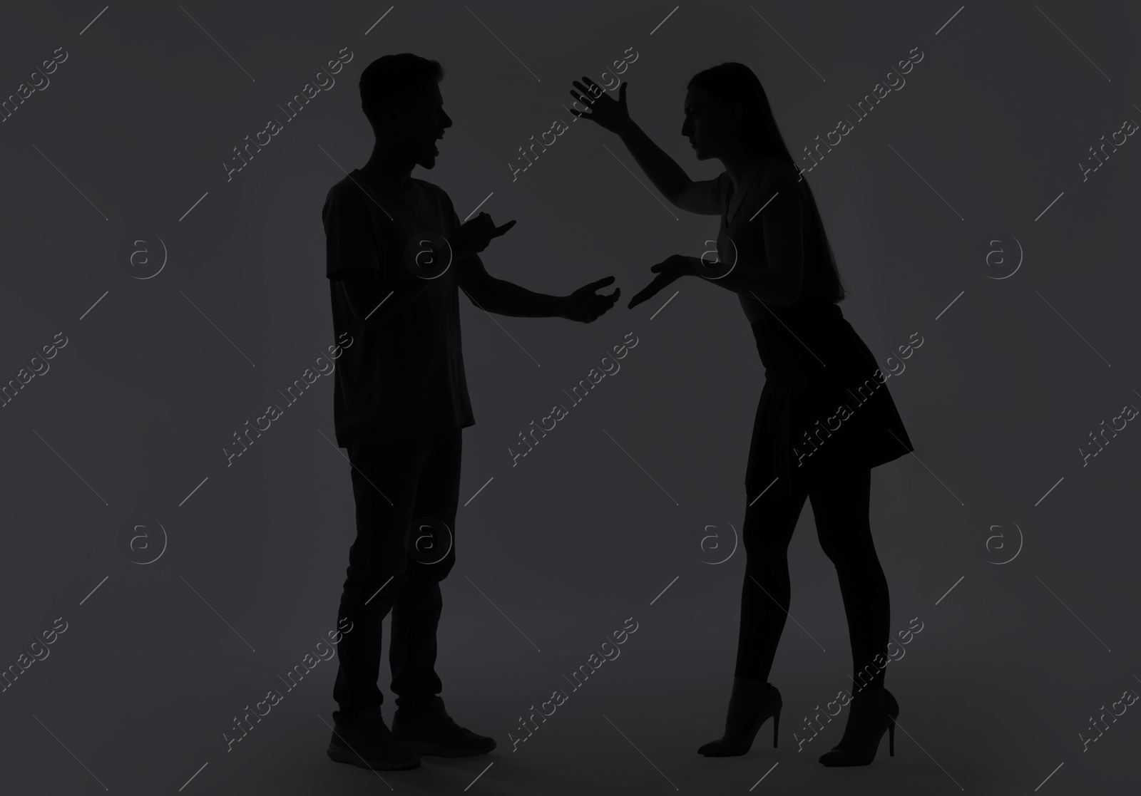 Photo of Domestic violence. Silhouette of couple quarreling on grey background