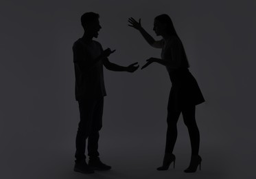 Photo of Domestic violence. Silhouette of couple quarreling on grey background