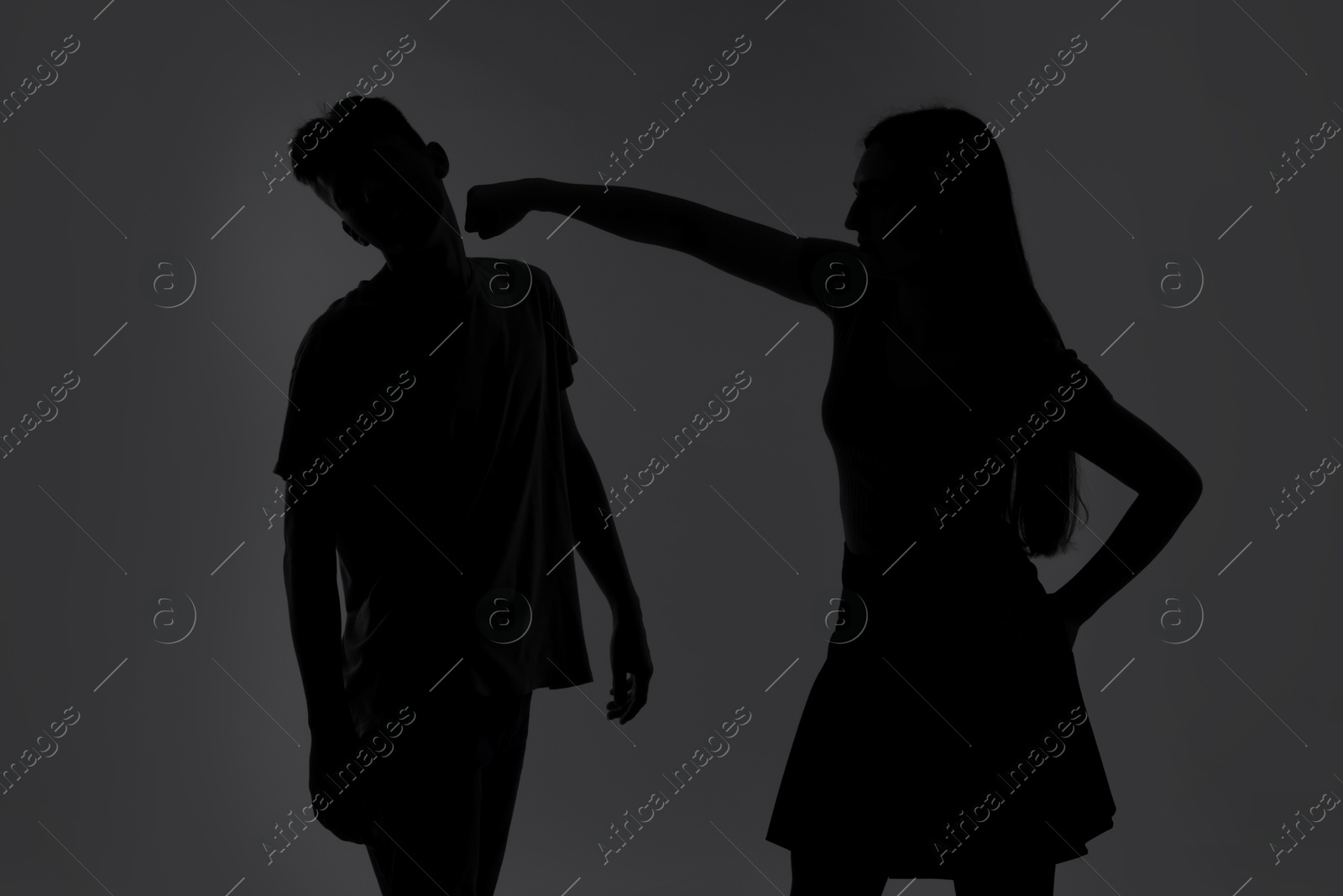 Photo of Domestic violence. Silhouette of woman punching her husband on grey background