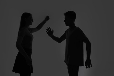 Photo of Domestic violence. Silhouette of couple quarreling on grey background