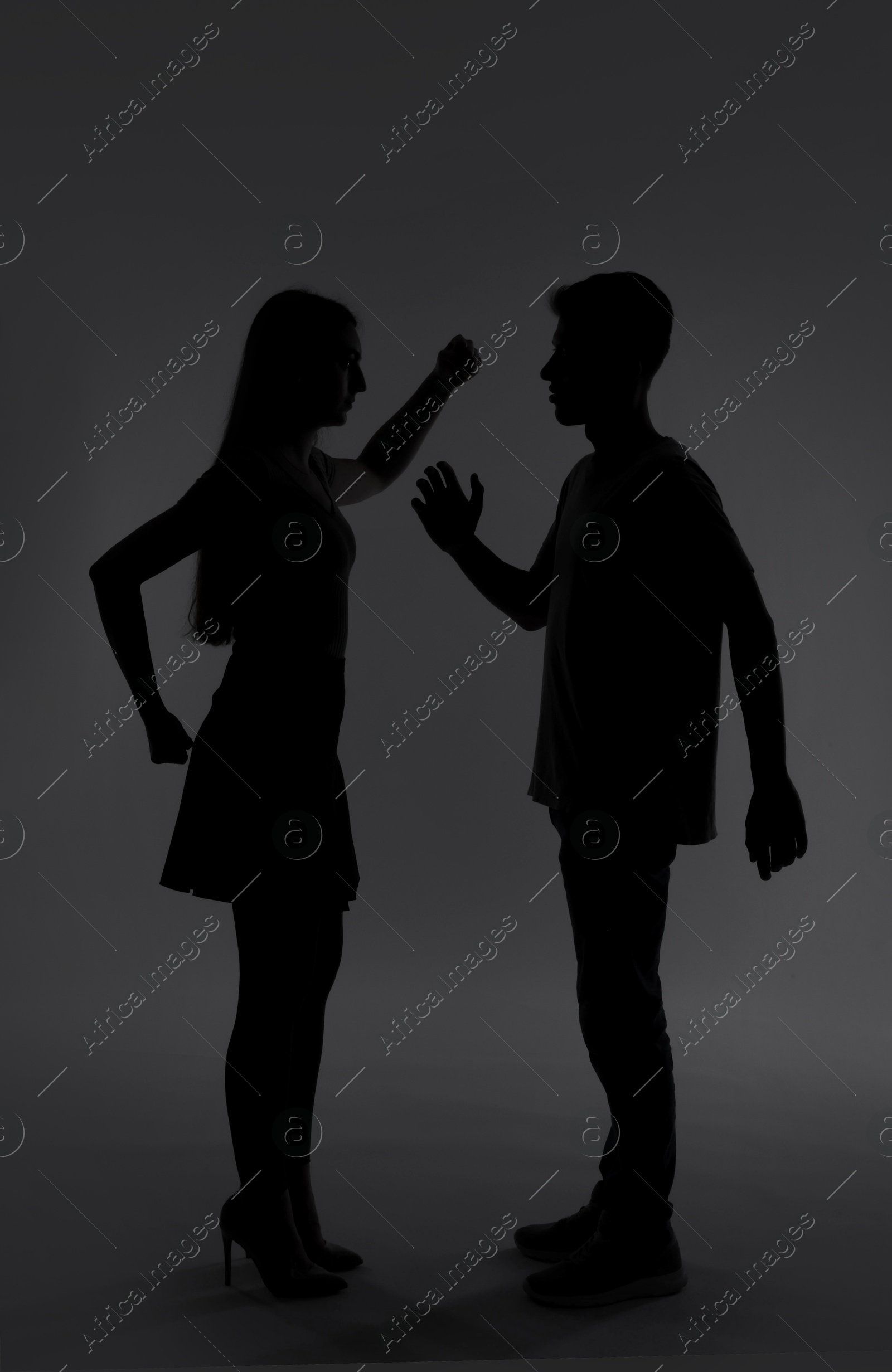 Photo of Domestic violence. Silhouette of couple quarreling on grey background