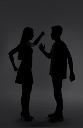 Photo of Domestic violence. Silhouette of couple quarreling on grey background