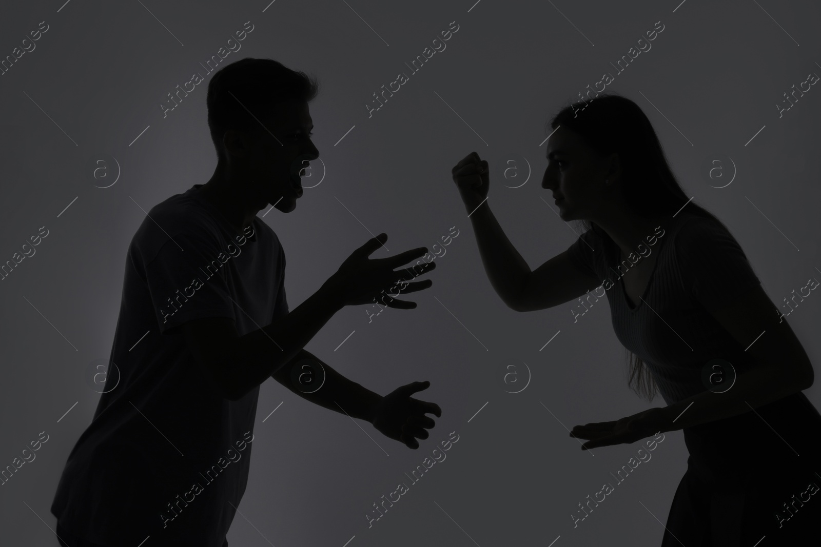 Photo of Domestic violence. Silhouette of couple quarreling on grey background