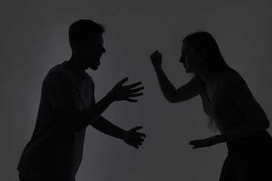 Domestic violence. Silhouette of couple quarreling on grey background