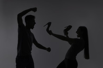 Photo of Domestic violence. Silhouette of man threatening his wife on grey background