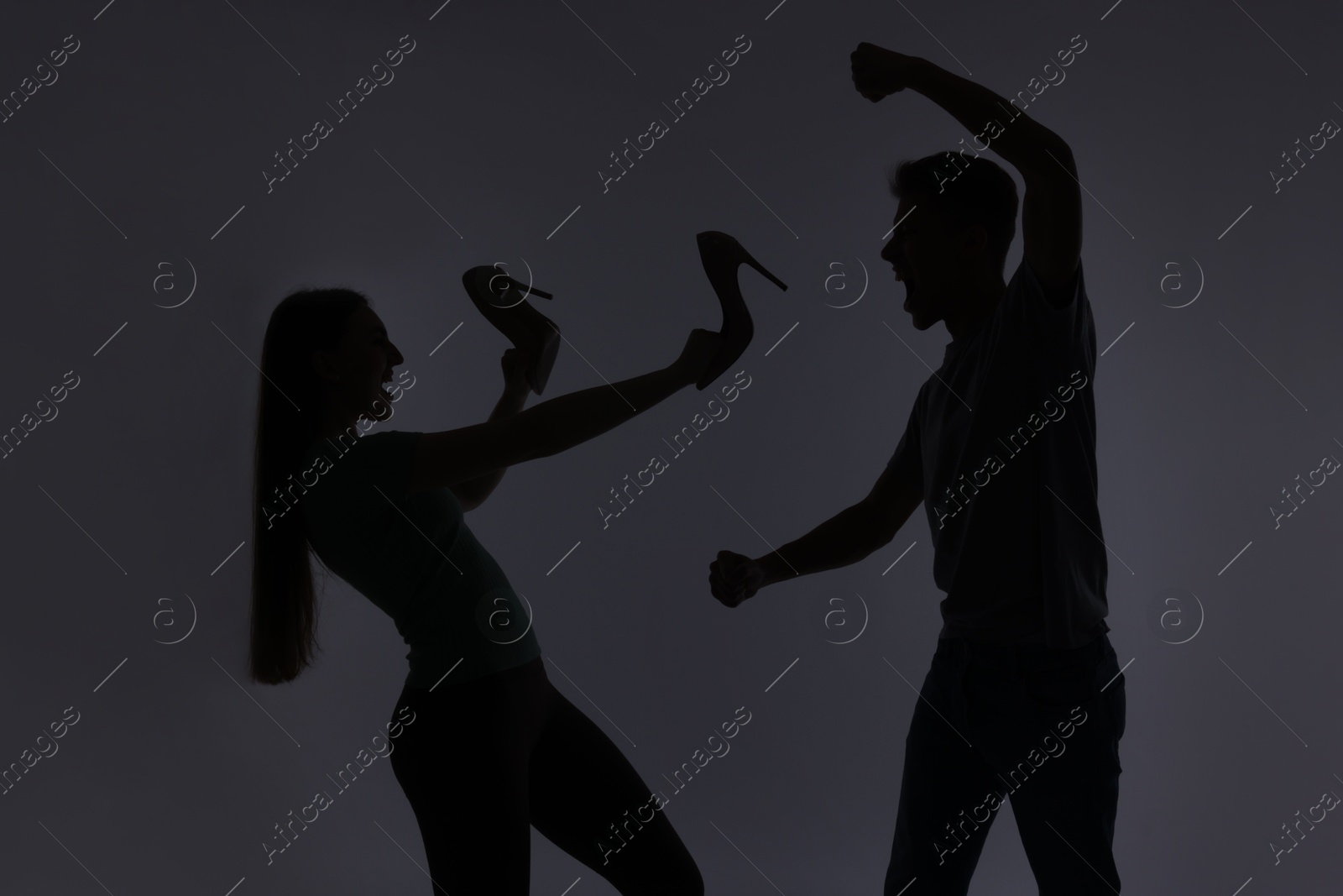 Photo of Domestic violence. Silhouette of man threatening his wife on grey background