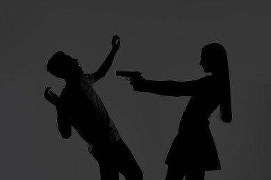 Domestic violence. Silhouette of woman with gun threatening her husband on grey background