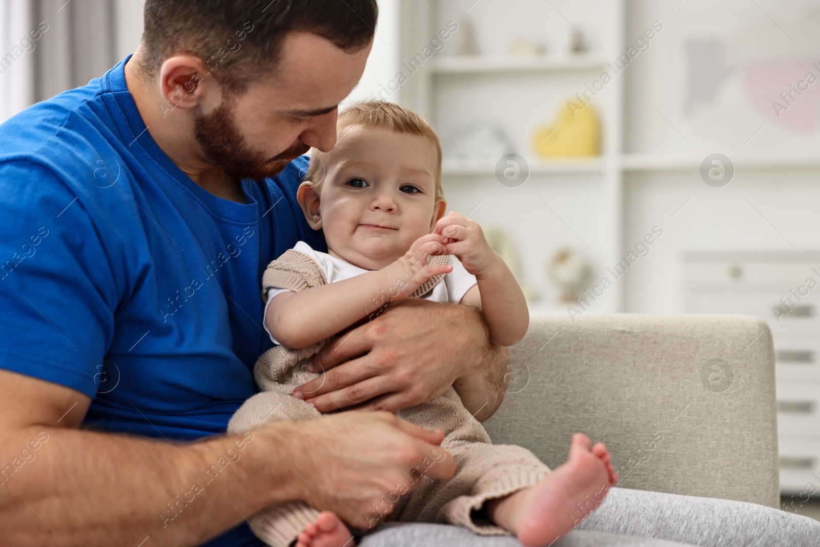 Photo of Father with his little baby on sofa at home. Space for text