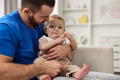 Photo of Father with his little baby on sofa at home. Space for text