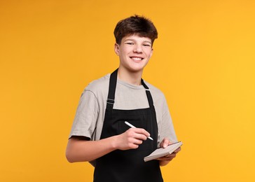 Photo of Boy with notepad taking order in cafe. Work for teenagers