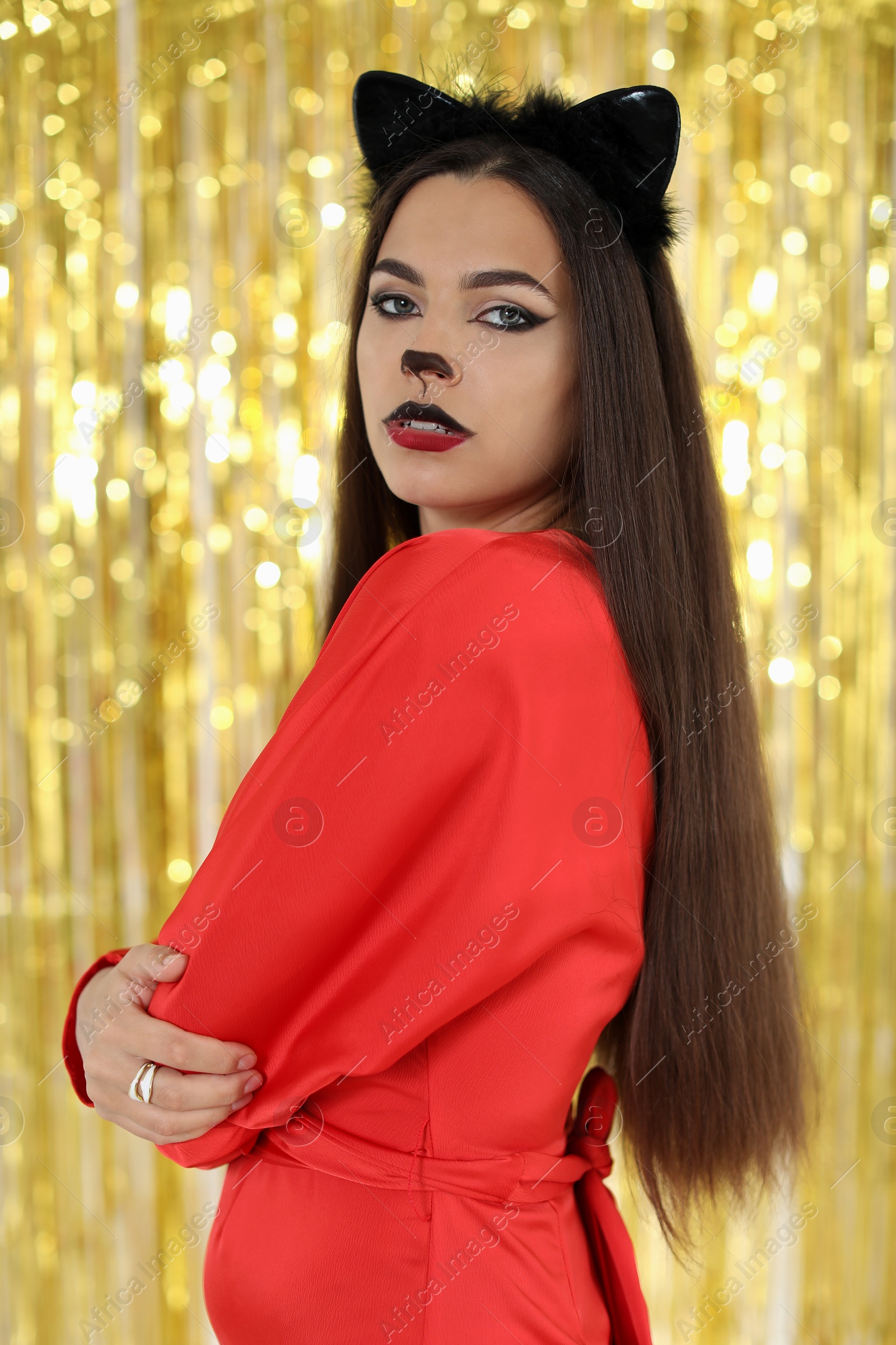 Photo of Beautiful woman with cat makeup and ears on golden background