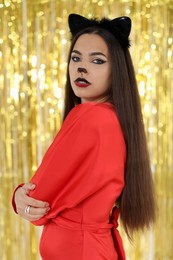 Beautiful woman with cat makeup and ears on golden background