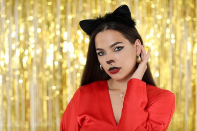 Photo of Beautiful woman with cat makeup and ears on golden background