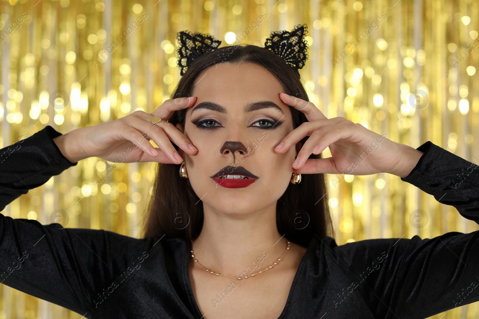 Photo of Beautiful woman with cat makeup and ears on golden background