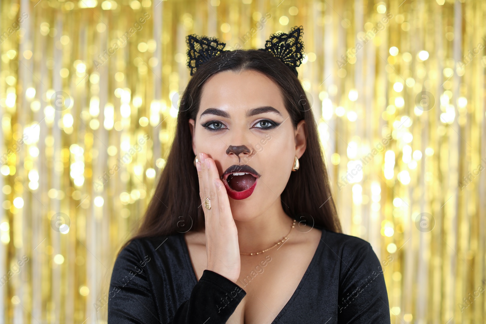 Photo of Emotional woman with cat makeup and ears on golden background