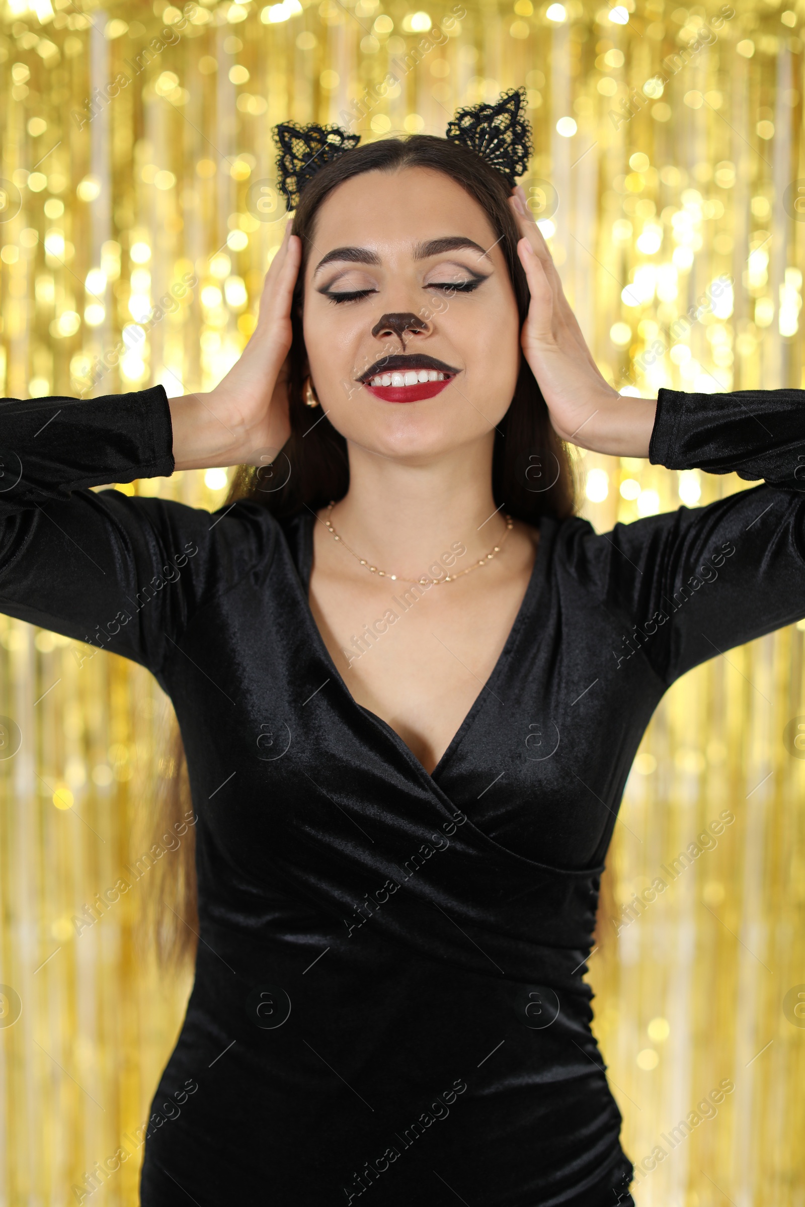 Photo of Beautiful woman with cat makeup and ears on golden background