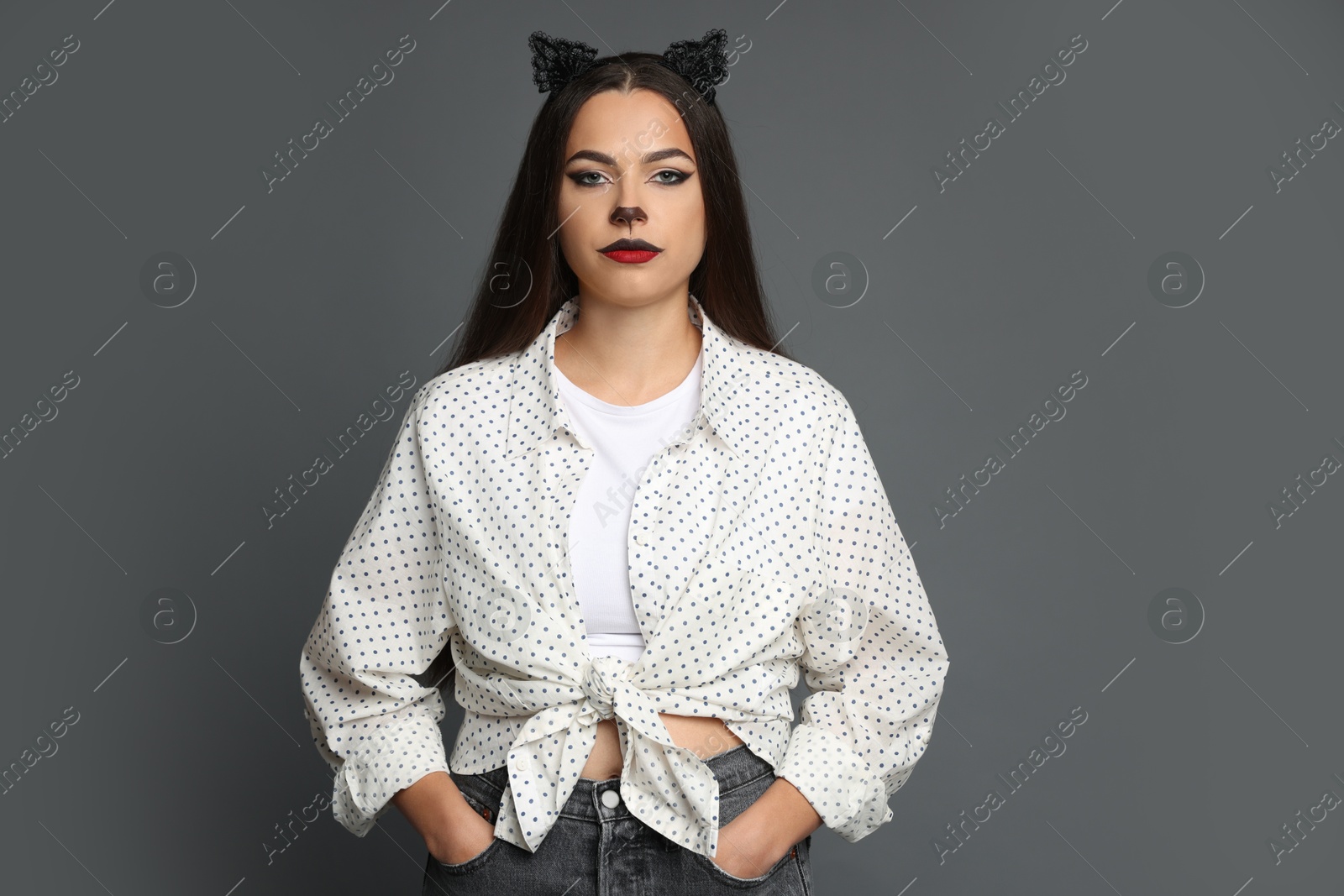 Photo of Attractive woman with cat makeup and ears on grey background