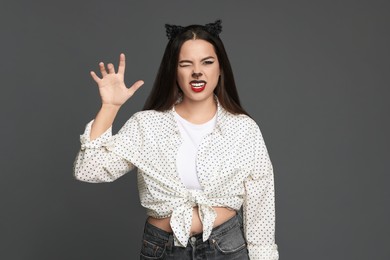 Photo of Playful woman with cat makeup and ears on grey background